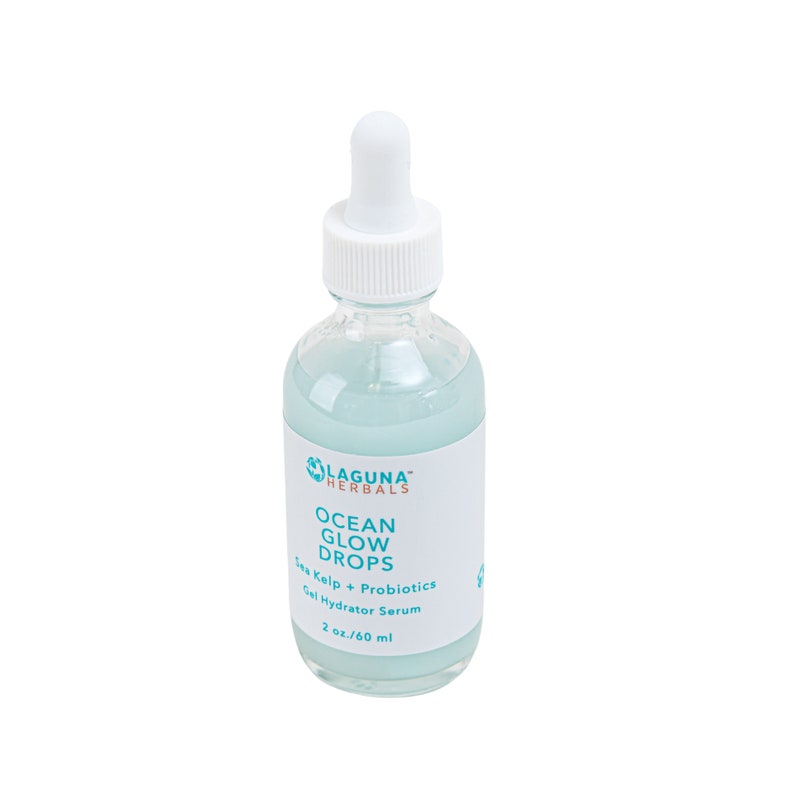 May include: A clear glass bottle with a white dropper top filled with a light blue liquid. The bottle is labeled "Laguna Herbals Ocean Glow Drops Sea Kelp + Probiotics Gel Hydrator Serum 2 oz/60 ml."