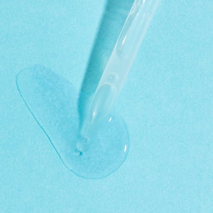 May include: A clear glass dropper bottle with a blue liquid dripping onto a light blue surface.