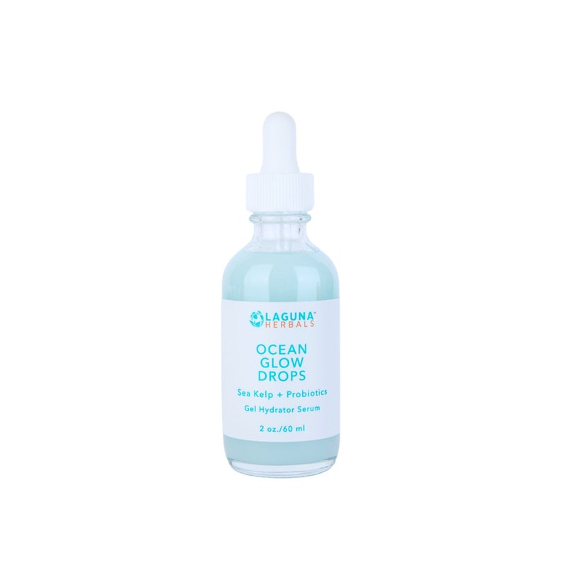 May include: A clear glass bottle with a blue liquid inside. The bottle has a white dropper top and a white label with the text "LAGUNA HERBALS OCEAN GLOW DROPS Sea Kelp + Probiotics Gel Hydrator Serum 2 oz./60 ml".