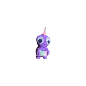May include: A purple figurine of a creature with large eyes and a unicorn horn. The figurine is holding a sign that says "Sweet". The creature is a whimsical design, likely handmade.