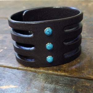 May include: A brown leather cuff bracelet with three turquoise stones set in silver.