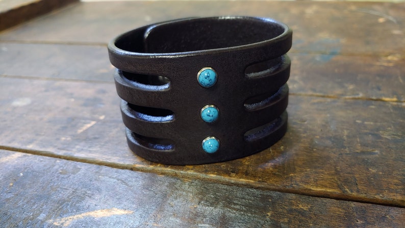 May include: A brown leather cuff bracelet with three turquoise stones set in silver.
