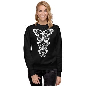 May include: Black sweatshirt featuring a white graphic of three butterflies stacked vertically. The butterflies are outlined in white and have the word "SOUL" written on the wings of the largest butterfly.