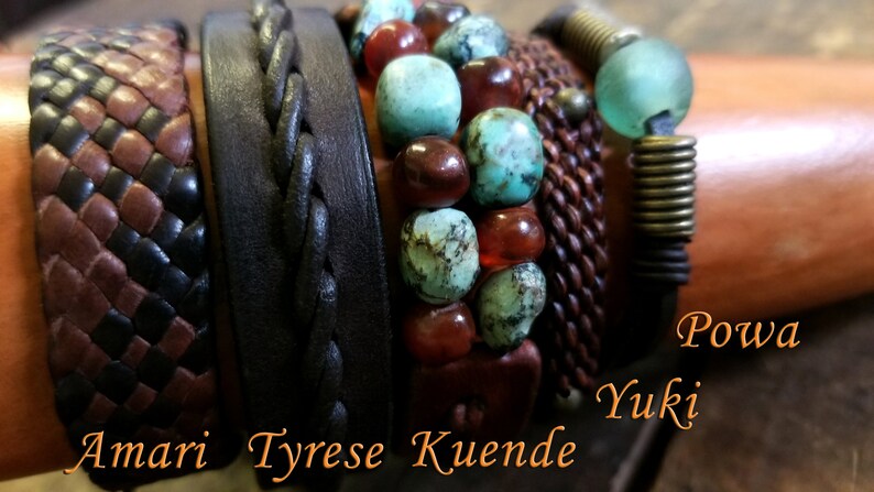 Puede incluir: Un conjunto de seis pulseras de cuero con diferentes texturas y colores. Las pulseras incluyen una pulsera de cuero trenzada, una pulsera de cuero tejida, una pulsera de cuentas con piedras turquesa y cornalina, una pulsera de cuero tejida con un cierre de metal, una pulsera de cuero con un resorte de metal y una pulsera de cuero con una cuenta de vidrio. Las pulseras est&aacute;n etiquetadas con los nombres "Amari", "Tyrese", "Kuende", "Yuki" y "Powa".