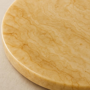 Puede incluir: Primer plano de una superficie redonda de mármol beige dorado con intrincados patrones de vetas. La superficie pulida tiene un acabado liso y brillante. El texto de la imagen dice: Ulha high resolution macro clisse up of the golden beigo marble lary ouaad surface-9sicm (ound boarl) Actailed lexlura.