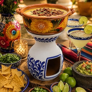 Puede incluir: Una mesa festiva con un cuenco de cerámica con queso con chorizo, cócteles de margarita, guacamole y totopos. El cuenco de queso está sobre un soporte decorativo. Acentos florales y limas frescas completan la escena.