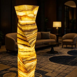 May include: A tall, illuminated onyx floor lamp with a unique, twisted design. The lamp features warm yellow and brown tones, creating a soft, inviting glow. The lamp is a decorative element in a modern interior setting.