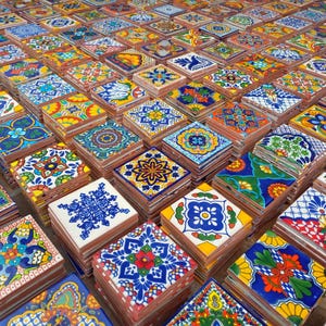 May include: A collection of colorful, hand-painted ceramic tiles with intricate designs. The tiles are stacked in rows and feature a variety of patterns, including floral, geometric, and abstract motifs. The tiles are a vibrant mix of blues, greens, yellows, reds, and oranges.