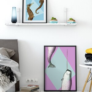 May include: Two framed art prints featuring sea creatures. One print shows two seahorses on a light blue background. The other print displays a narwhal with a long tusk against a pink and blue diamond.