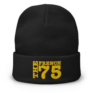 May include: Black beanie hat with the text "THE FRENCH 75" in yellow. The hat is a classic style, suitable for cold weather. The text is in a bold, stylized font.