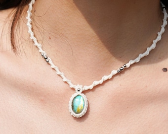 May include: A white macrame necklace with a silver bead accent and a light blue oval gemstone pendant.