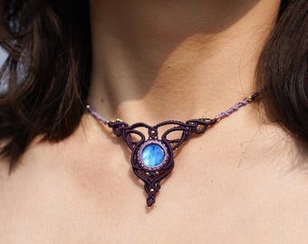 May include: A purple and gold macrame necklace with a blue gemstone pendant.