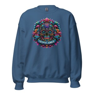 May include: A dark blue sweatshirt featuring a colourful skull design with a bitcoin symbol in the eye sockets. The skull is surrounded by floral patterns and a banner that reads "CRYPTO JUNKIE".