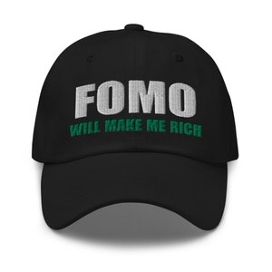 Puede incluir: Gorra de béisbol negra con el texto bordado en blanco "FOMO WILL MAKE ME RICH" en verde.