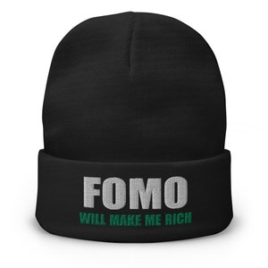 Puede incluir: Gorro negro con texto blanco que dice "FOMO WILL MAKE ME RICH" con texto verde debajo.