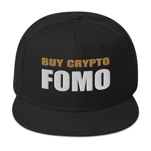 Puede incluir: Gorra de béisbol bordada en blanco y negro con el texto "BUY CRYPTO FOMO" en marrón y blanco.