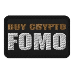 Puede incluir: Parche bordado negro con el texto "BUY CRYPTO FOMO" en letras blancas y marrones.