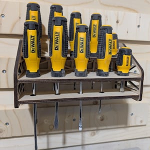 May include: A wooden wall-mounted organizer with eight yellow and black screwdrivers hanging from it. The screwdrivers are labeled "DEWALT".