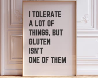 Può includere: Un poster bianco con cornice dorata, appeso a una parete bianca. Il poster ha testo nero che recita "Tollerò molte cose, ma il glutine non è una di queste."