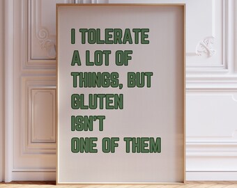 Può includere: Un poster bianco con cornice dorata, con il testo "I tolerate a lot of things, but gluten isn't one of them" in lettere verdi.