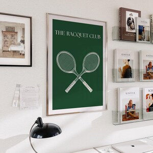 May include: A framed poster with a green background and white text that reads "THE RACQUET CLUB". Two white tennis rackets are crossed in the center of the poster.