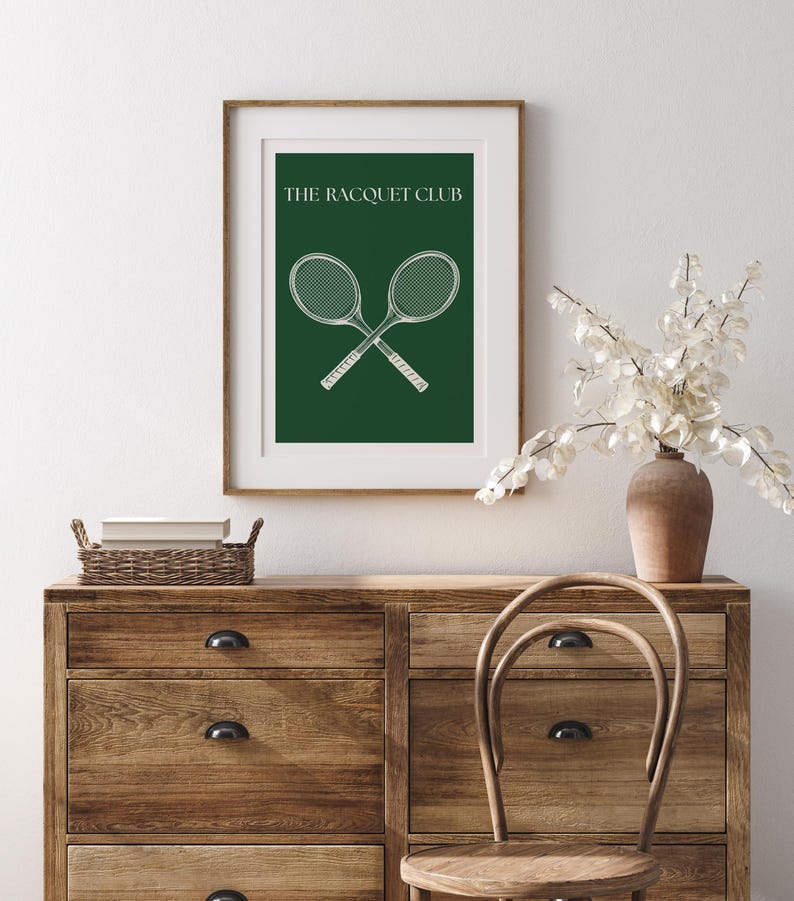 May include: A framed print with a green background and white text that reads "The Racquet Club". Two white tennis rackets are crossed in the center of the print.