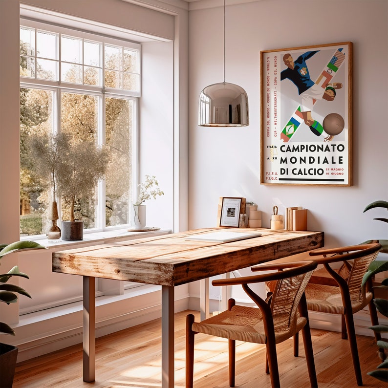 May include: A wooden table with a rustic finish sits in a room with a large window. Two chairs with woven seats are positioned at the table. A poster with the text "Campionato Mondiale di Calcio" hangs on the wall.