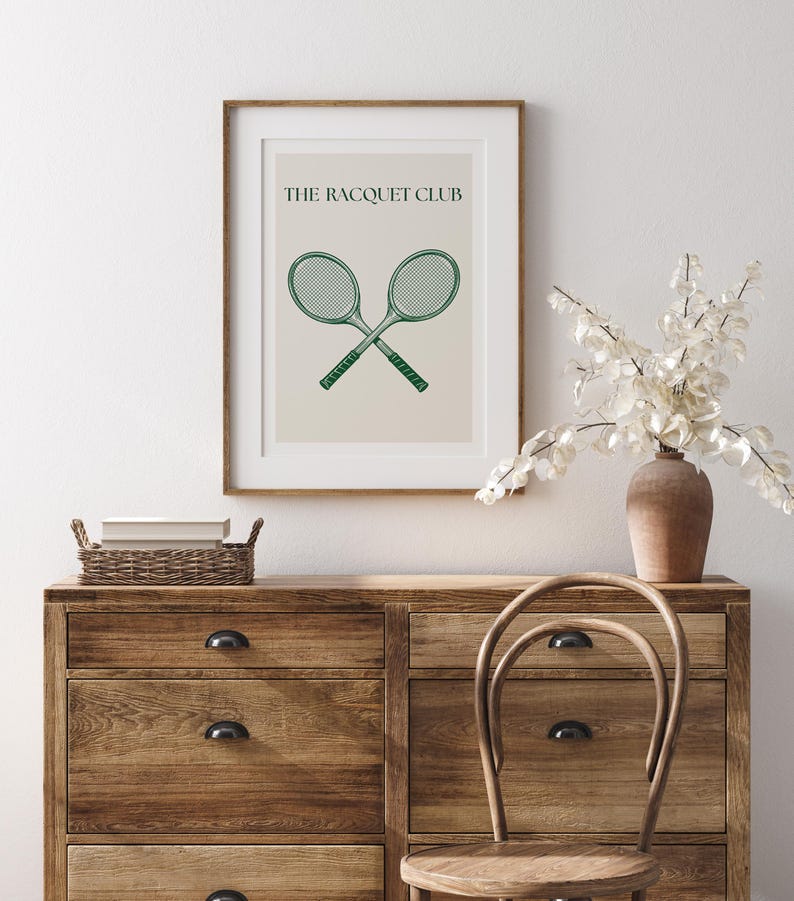 Puede incluir: Una impresi&oacute;n enmarcada con un fondo beige y el texto "THE RACQUET CLUB" en negro. Dos raquetas de tenis verdes se cruzan en el centro de la impresi&oacute;n.