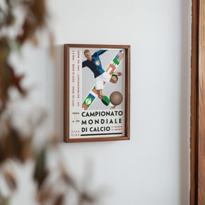 May include: A framed poster with a vintage design featuring a football player in a blue jersey kicking a ball. The poster is titled "Campionato Mondiale di Calcio" with the dates "27 Maggio" and "10 Giugno" printed below.