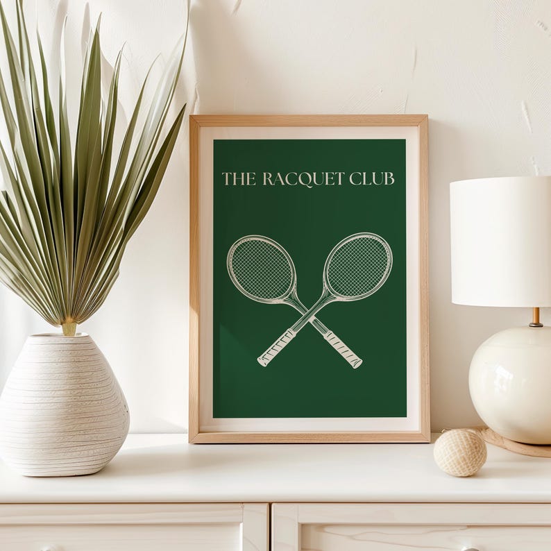 May include: A framed print with a green background and white text that reads "THE RACQUET CLUB". Two white tennis rackets are crossed in the center of the print.