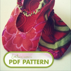 May include: A pair of red, green, and pink fabric baby shoes with a floral pattern. The shoes have elastic around the ankle and are made of soft fabric. The image includes the text "patsy patterns PDF PATTERN".