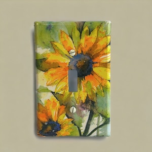 May include: A light switch cover with a watercolor design of sunflowers in shades of yellow, orange, and green.