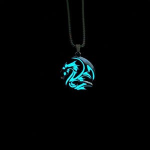 Peut inclure: Un collier pendentif dragon bleu brillant sur fond noir. Le pendentif présente un motif de dragon stylisé qui émet une lumière bleu vif. La chaîne du collier est de couleur métallique foncée.