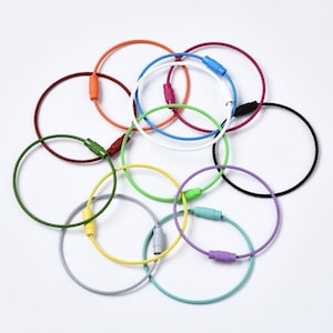 May include: Assortment of colorful metal key rings with a cable construction. The key rings are in various colors, including red, green, blue, yellow, purple, and black.