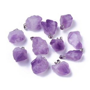 May include: A collection of amethyst crystal pendants. Each pendant features a raw, irregular purple amethyst stone with a silver-colored metal loop for attaching to a chain or cord. The crystals vary in shape and size.