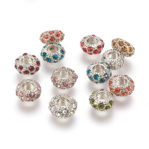 May include: Assortment of 10 silver-toned round spacer beads with a variety of colored rhinestones. Each bead has a hole in the center for stringing.