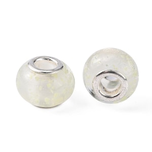 May include: Two white glass beads with a silver metal ring. The beads have a speckled, glittery appearance.