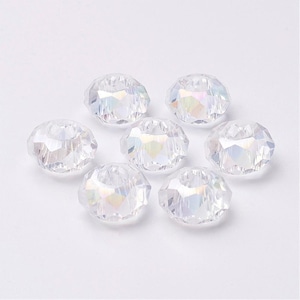 May include: Seven clear iridescent glass beads with a faceted design. The beads are round and have a hole in the center.