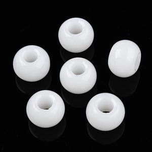 May include: Six white round beads with a hole in the center. The beads are smooth and glossy.