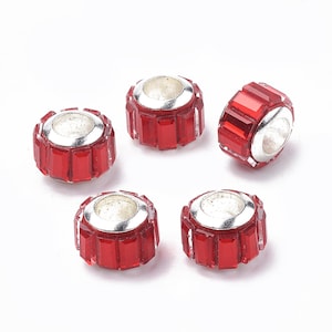 May include: Five red crystal beads with silver accents. The beads are round and have a hole in the center for threading.