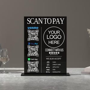 May include: Black and white sign with the text "SCAN TO PAY" and QR codes for various payment methods, including Venmo, PayPal, Cash App, Apple Pay, Visa, and Google Pay. The sign also includes the text "YOUR LOGO HERE" and "CONNECT WITH US" with social media icons.