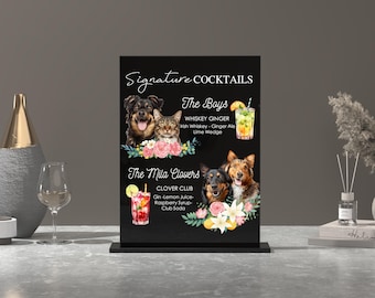 May include: Black chalkboard sign with a white frame and a stand. The sign has a list of signature cocktails with illustrations of dogs and cats. The cocktails are called "The Boys" and "The Mila Clovers".