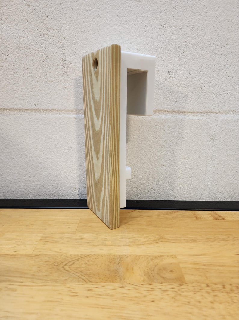May include: A wooden wall mount with a white plastic bracket. The mount has a natural wood grain finish and a small hole in the top.