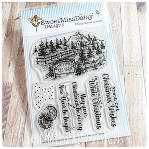May include: A set of clear photopolymer stamps by SweetMissDaisy Designs featuring a detailed illustration of a Christmas tree farm with a barn, fence, and pine trees, alongside text stamps reading Christmas Tree Farm, Fresh-Cut Christmas Wishes, I'm dreaming of a White Christmas, and May your Christmas be merry and New Year be bright.