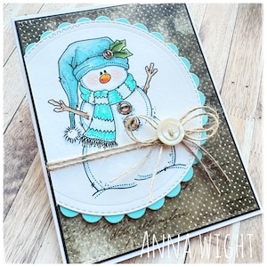 May include: A handmade Christmas card featuring a snowman with a blue hat, a striped scarf, and a holly sprig. The card has a scalloped edge and is decorated with twine and a button.