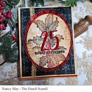 May include: A handmade Christmas card with a black background featuring white snowflakes and a red oval frame. Inside the frame is a holly design with the number 25 and the words "merry christmas". The card has a wooden frame and gold lace.