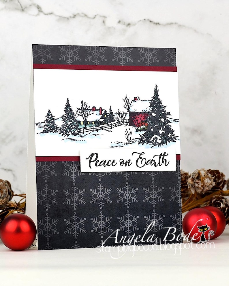 May include: A handmade Christmas card featuring a winter scene with a red barn and snow-covered trees. The card has a dark gray snowflake pattern and the words "Peace on Earth". Red ornaments are in the foreground.