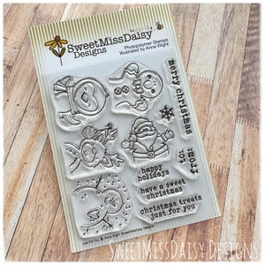 May include: Clear photopolymer stamps featuring Christmas-themed designs, including a snowman, Santa Claus, and reindeer. The set includes text stamps with holiday greetings like "Merry Christmas" and "Happy Holidays". The package is labeled "Sweet Miss Daisy Designs".