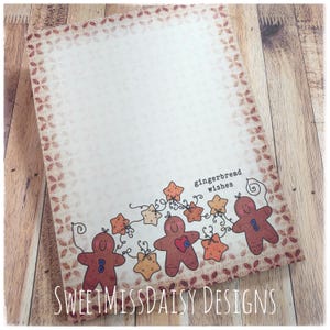 May include: A rectangular card featuring a brown gingerbread man pattern border and a bottom illustration of three brown gingerbread figures with blue buttons and orange stars connected by black swirls, with the text gingerbread wishes.