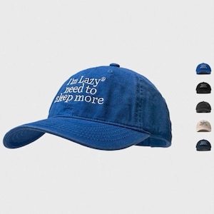 May include: A blue baseball cap with the text "I'm Lazy need to sleep more" embroidered in white. The cap has a curved peak and a button on top. Several other colour options are shown in the background.